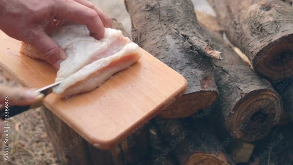 Man cut bacon on a wooden board with black knife Man cut bacon on a wooden board with black knife