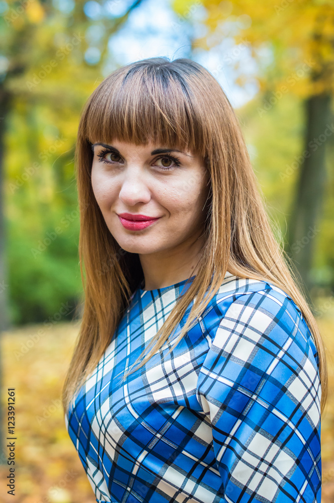 portrait of a beautiful, dreamy girl with long straight hair in a blue long dress in the park in autumn