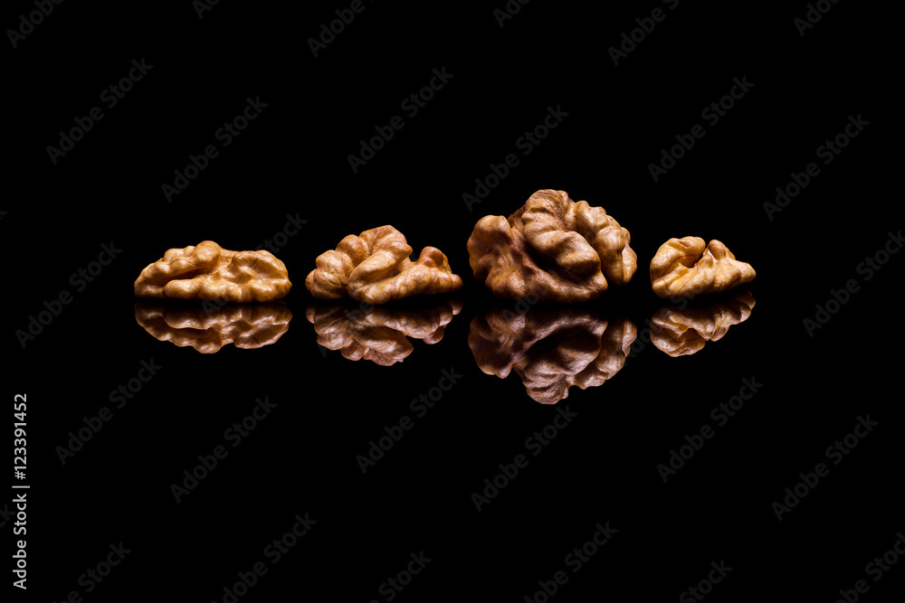 Obraz premium Four walnuts on black reflective background
