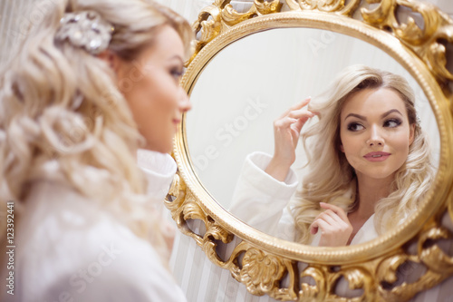 Принти на полотні Portrait of young sexy woman in a Bathrobe looking at the mirror.