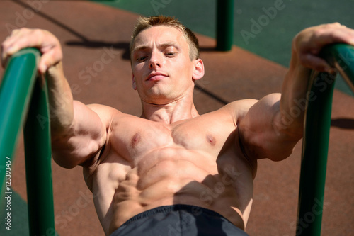 Muscular man practice street workout in an outdoor gym