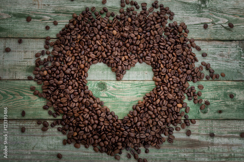 Coffee beans as heart on old rustic table. Top view © alexscr