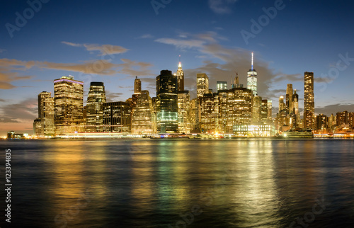 The Downtown Manhattan skyline at sunset with reflections on the East River © kmiragaya