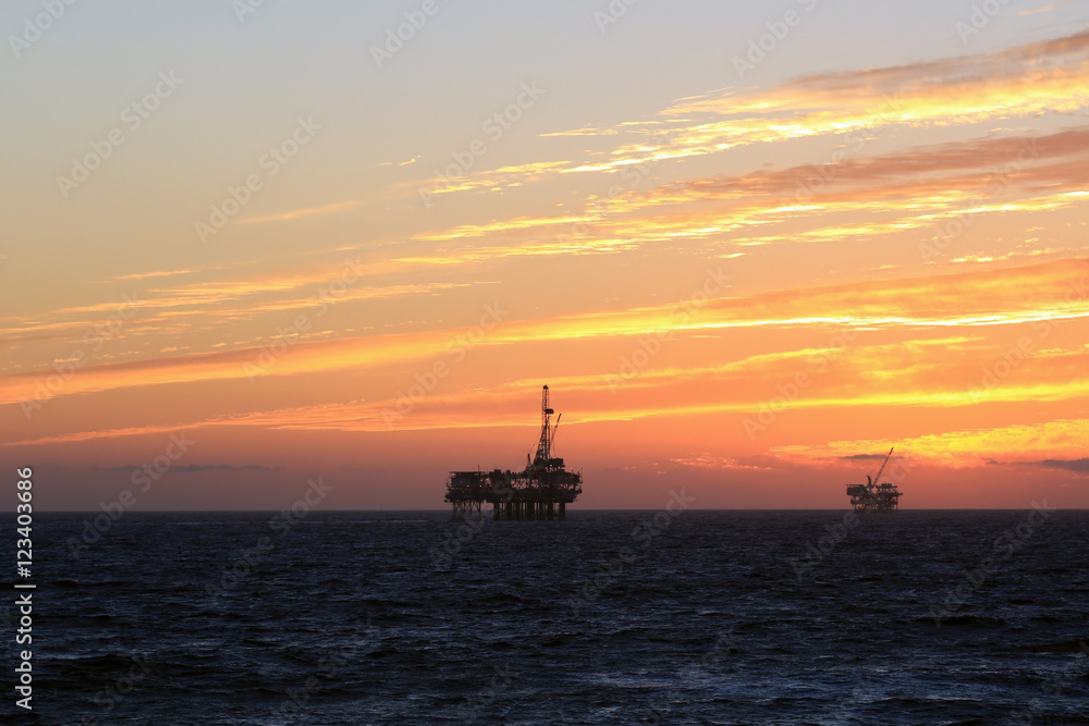 Beach oil rig platform at sunset