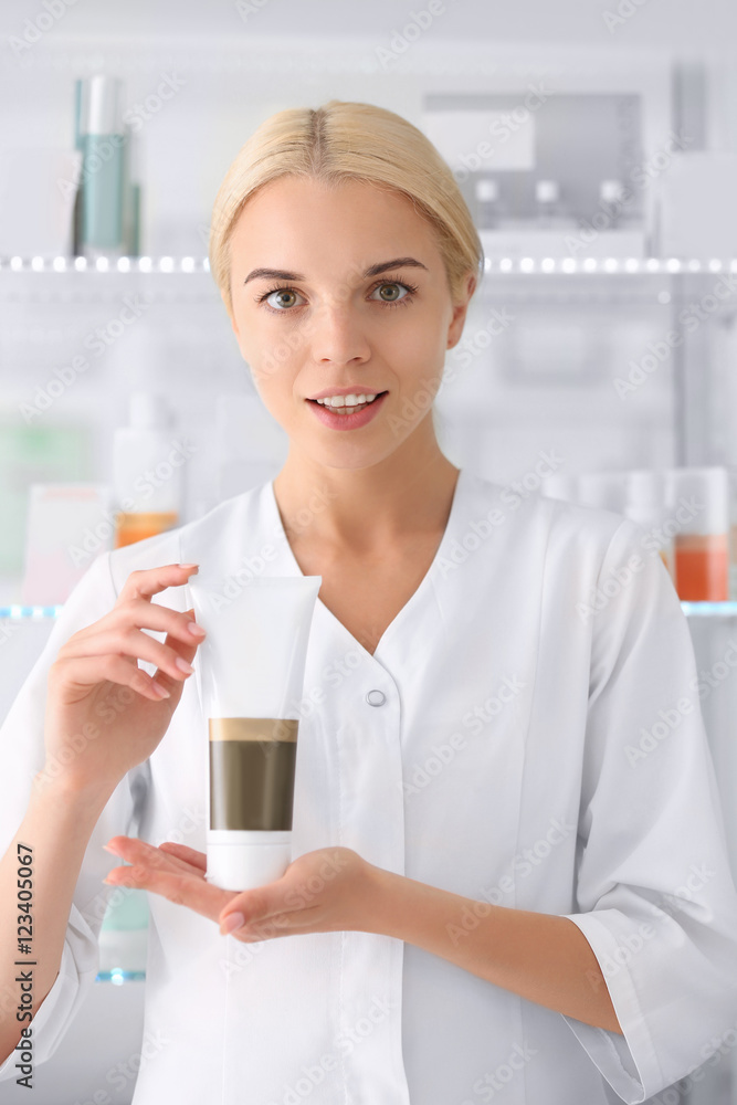 Cosmetologist holding cream beside showcases Cosmetologist holding cream beside showcases