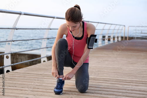 Young woman tying shoelaces...
