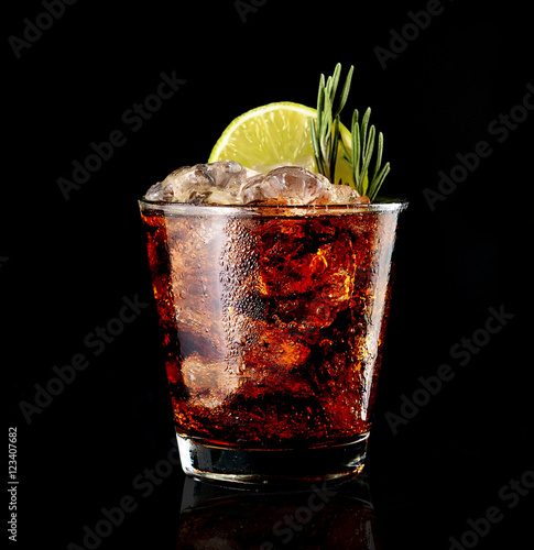 cola drink with ice and green lime on black background
