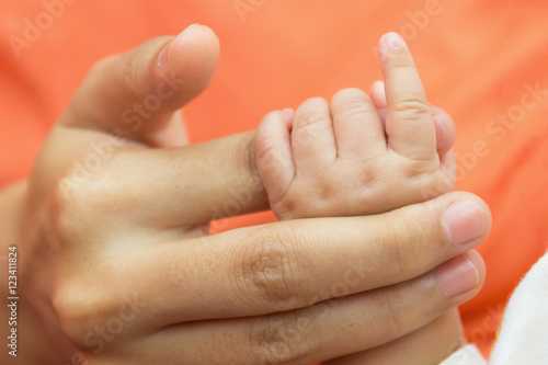 Hand new born baby holding hand mother.