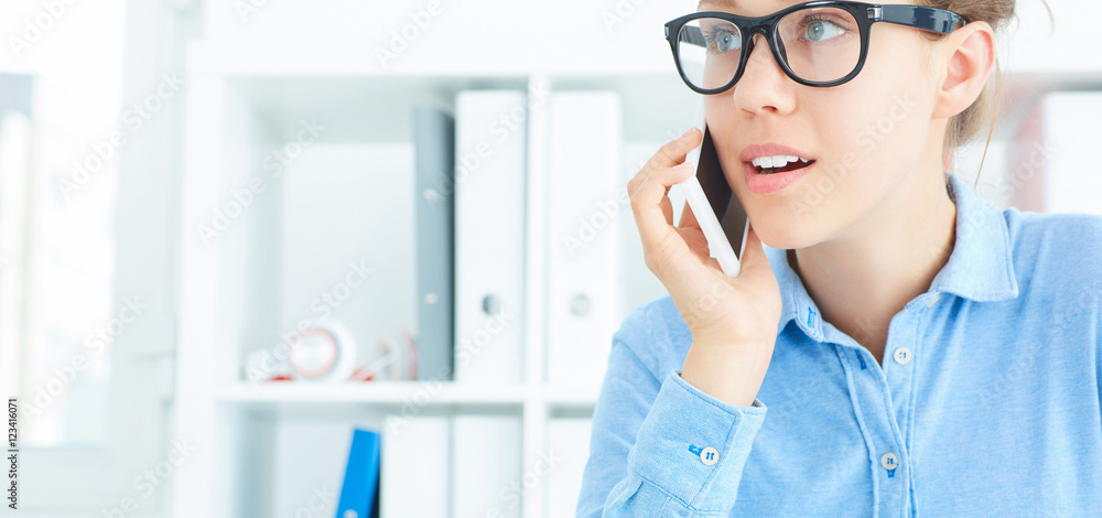 Closeup beautiful smiling young girl talking on the mobile phone in the office. Closeup beautiful smiling young girl talking on the mobile phone in the office.