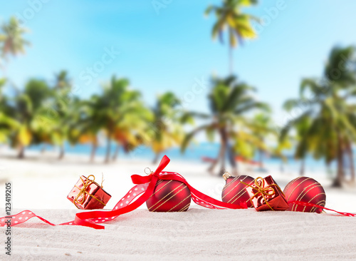 Christmas red balls, ornament on a beach - concept of a warm weather Christmas