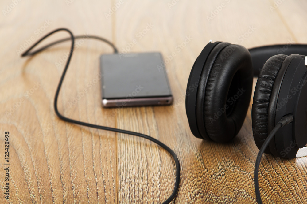 Headphones and phone on a wooden surface Headphones and phone on a wooden surface