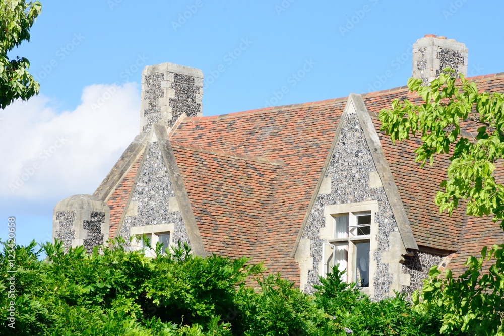 Large stone cottage behind green  trees