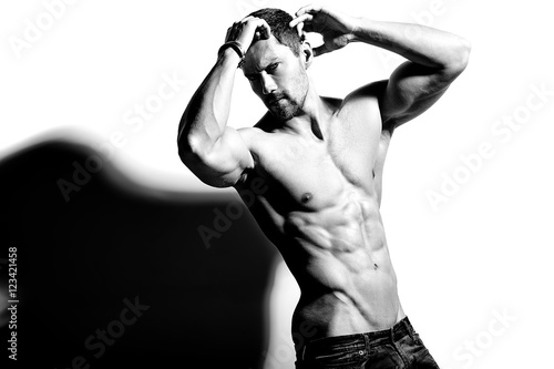 Portrait of strong healthy handsome Athletic Man Fitness Model posing near white wall © halayalex