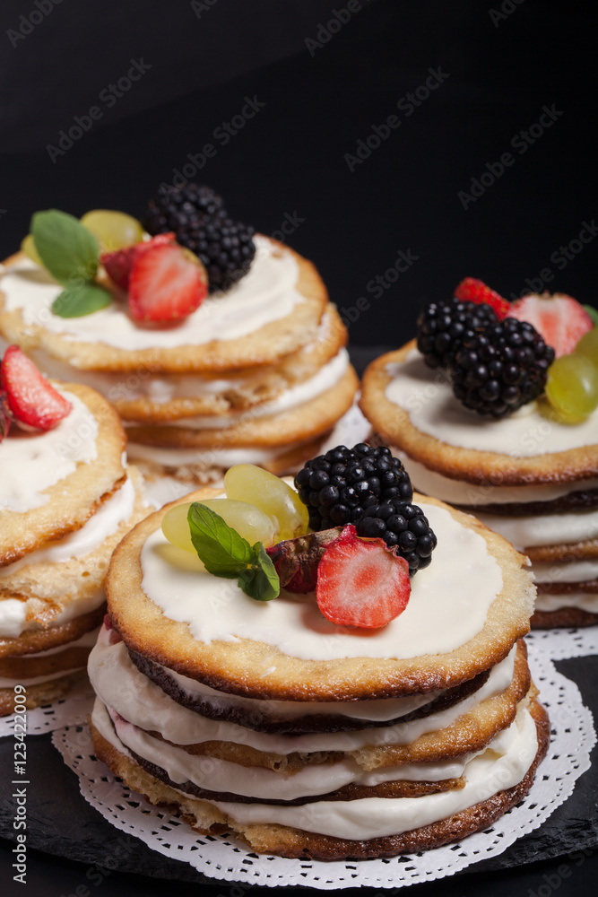 Biscuit homemade cake with cream and berries on black background