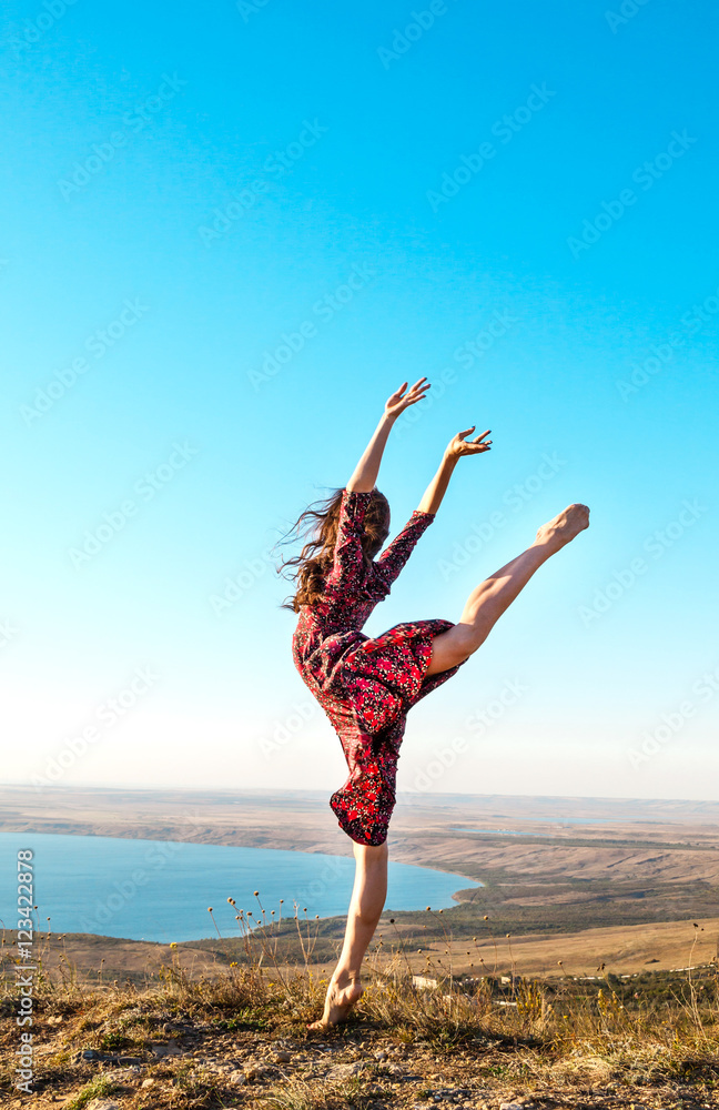 Fototapeta premium Beautiful young ballerina posing outdoor. Gymnast girl doing exercise in nature
