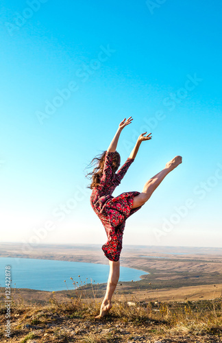 Beautiful young ballerina posing outdoor. Gymnast girl doing exercise in nature