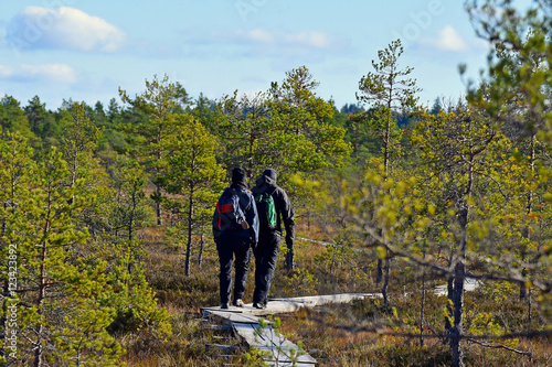 Couple trekking on a wooden hiking trail. © JRJfin