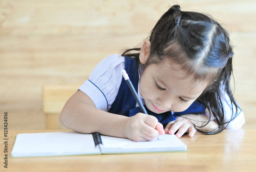 little girl writeng the notebook with pencil on the table school uniform little girl writeng the notebook with pencil on the table school uniform