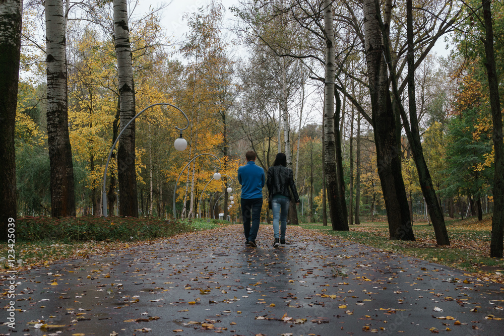 Fototapeta premium Loving couple walking along autumn park. View from the back