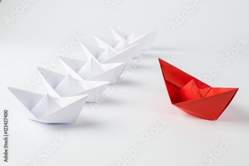 red paper ship leading among white