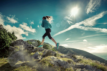 Female running in mountains under sunlight.