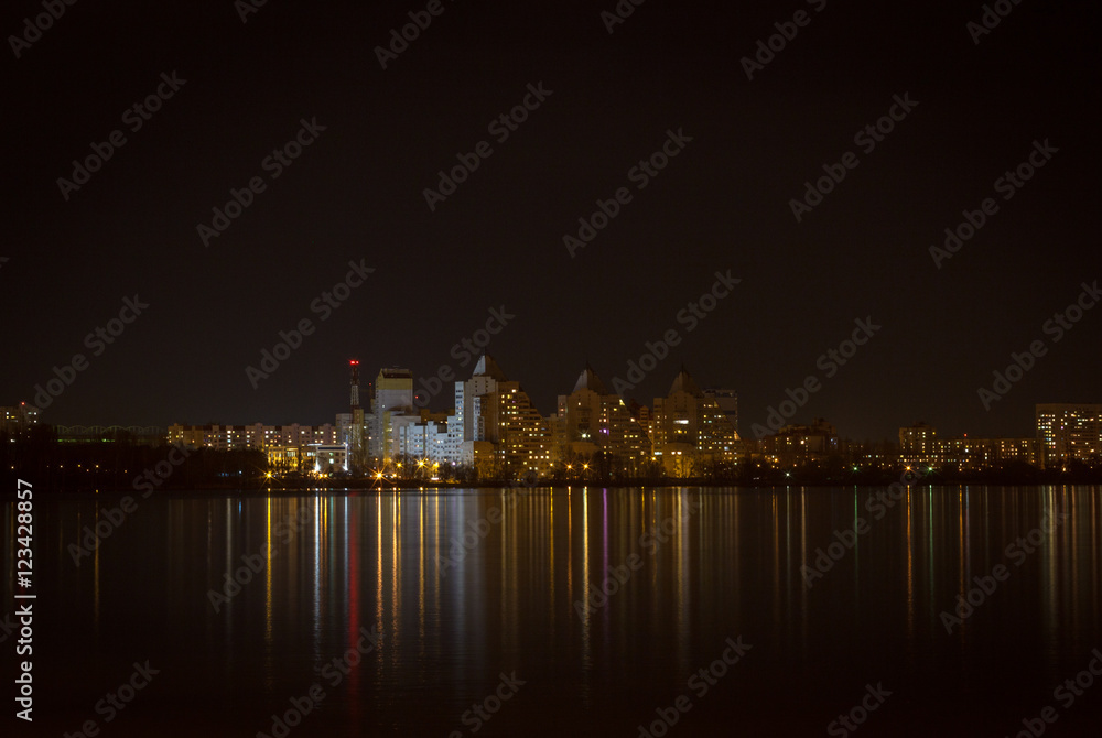 Night lights of city buildings reflected in the water. long exposure