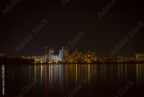 Night lights of city buildings reflected in the water. long exposure