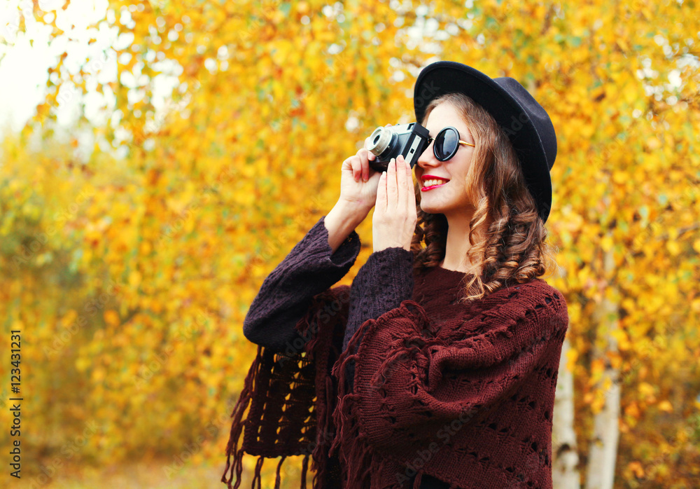 Autumn fashion smiling woman with retro vintage camera wearing b