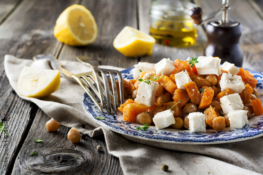 Warm salad of pumpkin, chickpeas and feta cheese on the old wooden background. Selective focus. Warm salad of pumpkin, chickpeas and feta cheese on the old wooden background. Selective focus.