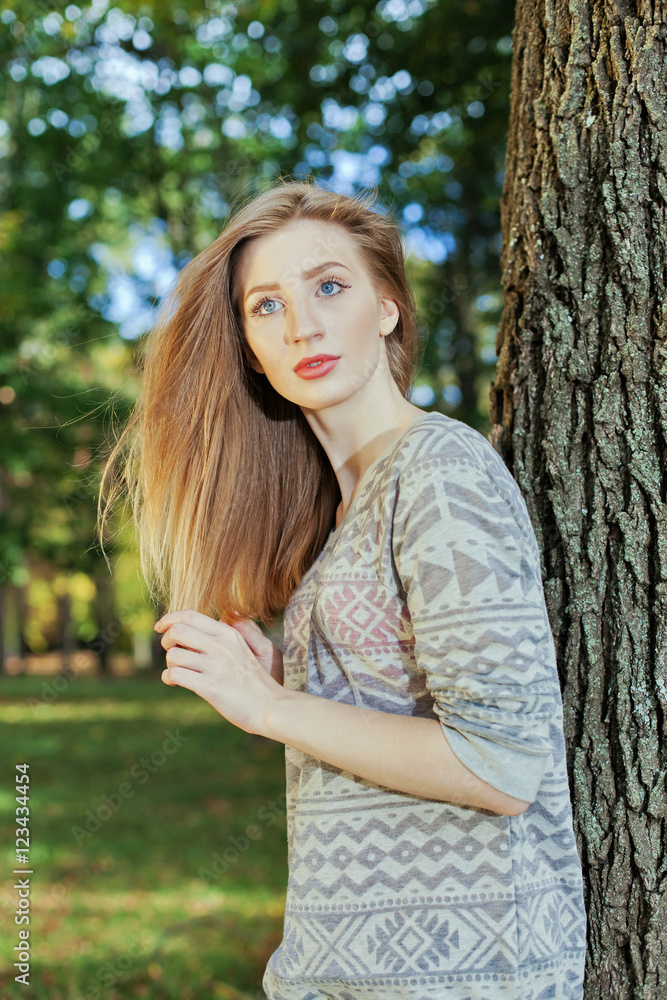 Beautiful woman with blue eyes standing in a park in autumn Beautiful woman with blue eyes standing in a park in autumn