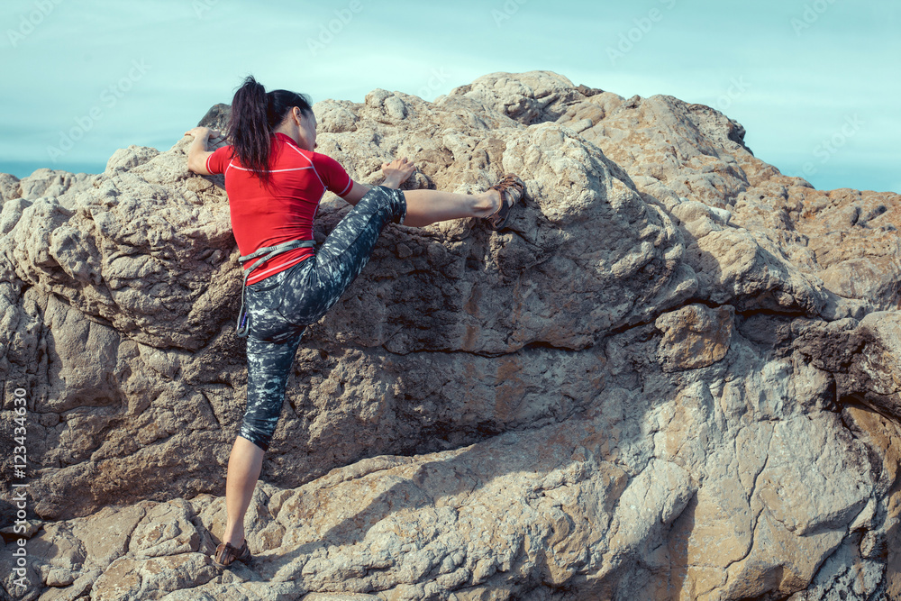 Naklejka premium happy woman climbs a rock while trekking outdoors