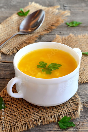 Pumpkin soup with potatoes, rice and parsley. Simple pumpkin soup in bowl on old wooden background, spoon, burlap. Vegetarian dish. Rustic style