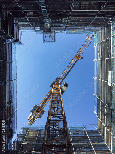 Directly below shot of crane and glass building against clear blue sky
