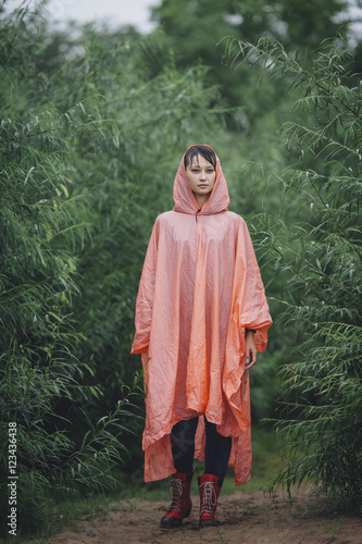 Portrait of woman wearing raincoat standing amidst plants during rainy season photo