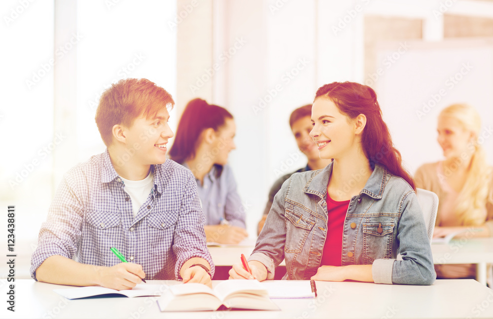two teenagers with notebooks and book at school two teenagers with notebooks and book at school