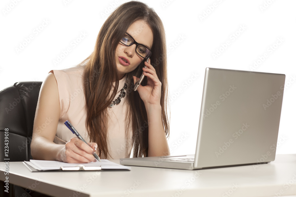 young business woman working on a laptop, talking on the phone and writes young business woman working on a laptop, talking on the phone and writes