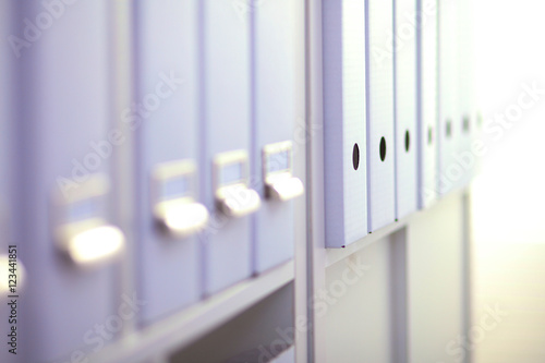 File folders, standing on shelves in the background