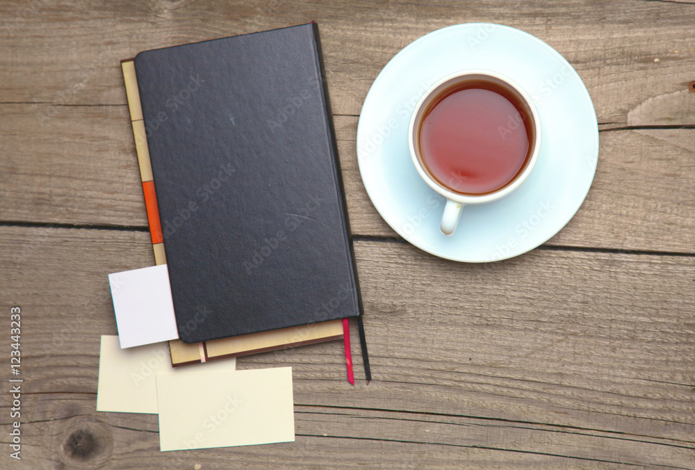 Blank business cards with pen, notebook and tea cup on wooden office table Blank business cards with pen, notebook and tea cup on wooden office table