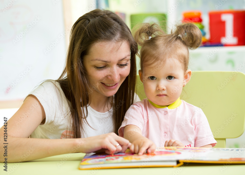 Mother reading book her kid daughter at table Mother reading book her kid daughter at table