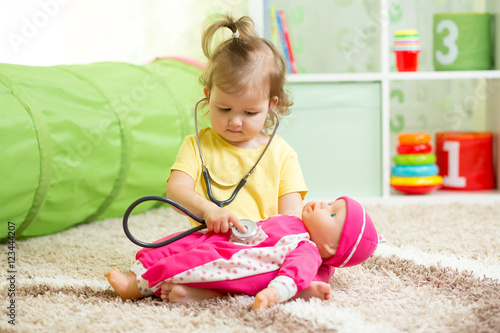 Child Girl Playing With A Doll In Playroom