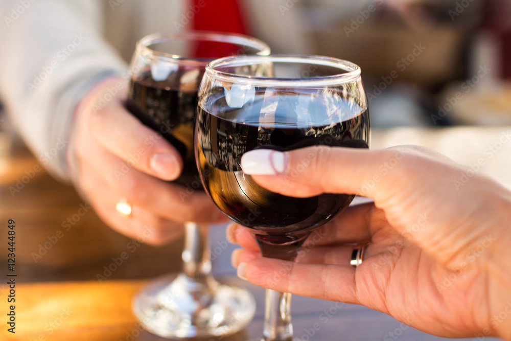 two glasses of wine in the hands of man and woman with a blurred background