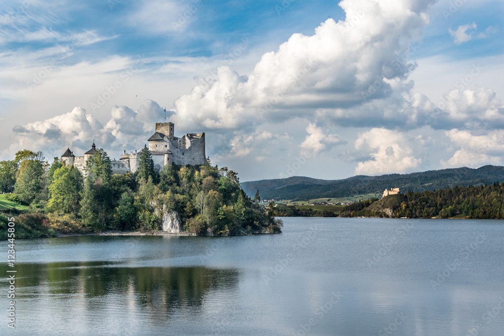 Castle on the shore of the lake in autumn day with a dramatic sky and white clouds