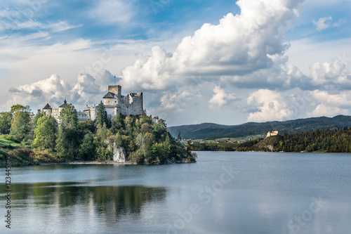 Castle on the shore of the lake in autumn day with a dramatic sky and white clouds