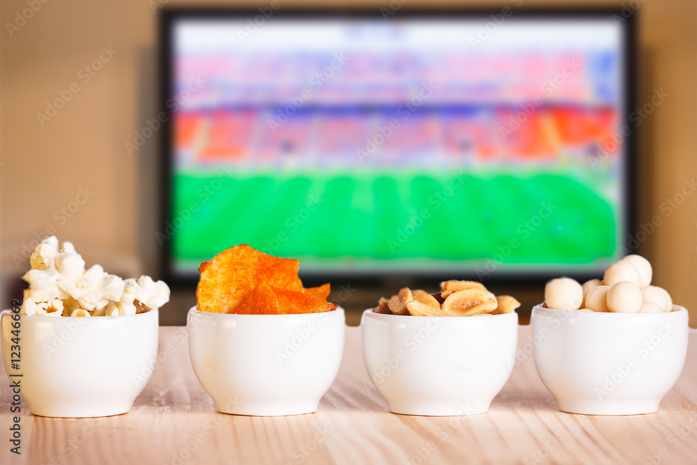 Small bowls of snacks on natural wooden table.