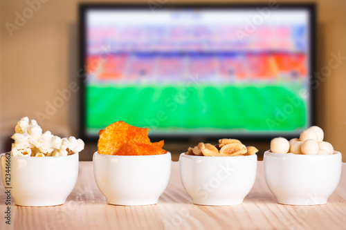 Small bowls of snacks on natural wooden table.
