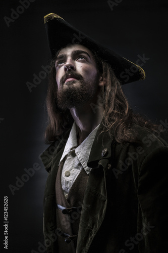 Portrait of a medieval bearded pirate thoughtfully looking up on a black background. photo