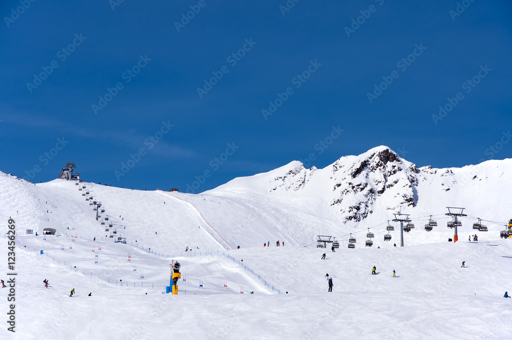 Skiers, chairlift and easy giant slalom course in Alpine ski resort in Solden in Otztal Alps, Tirol, Austria