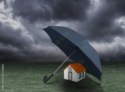 House insurance concept, house protected under umbrella, residential home real estate protection © Warakorn