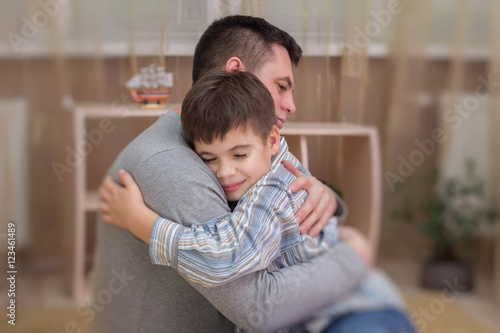 Sad son hugging his dad indoor