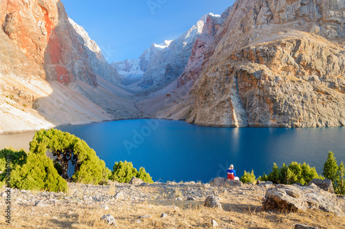 Lonely man sitting near Majestic mountain lake